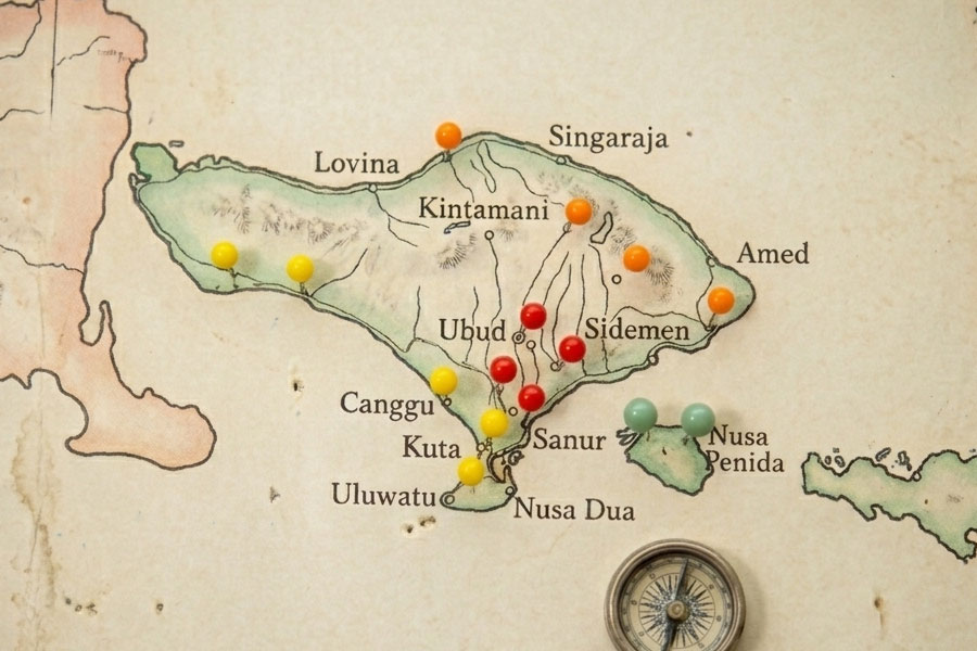 A close-up bali map of Indonesia with colorful pins marking locations such as Ubud, Kuta, Sanur, and Lovina. A small compass is visible in the lower right corner.